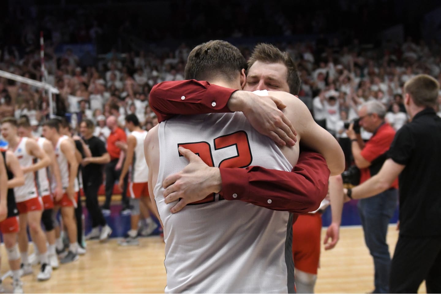 Men's volleyball coach embracing one of his athletes after a match